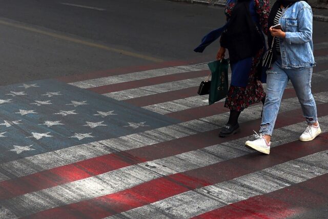 Iranians walk across a street painted with a US flag in Tehran, where citizens are dubious