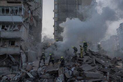 Rescuers work at a residential building partially destroyed following Russian drones and m