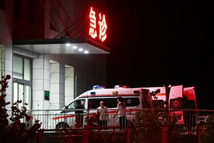 Men stand beside ambulances at the cordoned-off Qinyuan County People's Hospital, 20