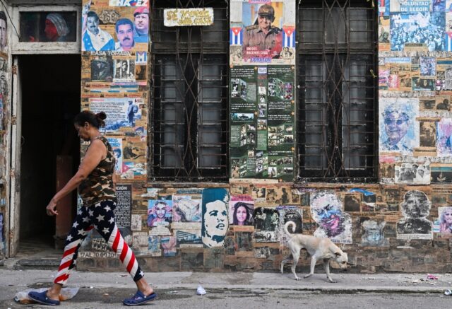 A woman in Havana leggings bearing the flag of the United States walks past a house displa
