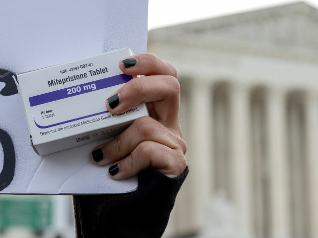 FILE - An abortion-rights activist holds a box of mifepristone pills as demonstrators from