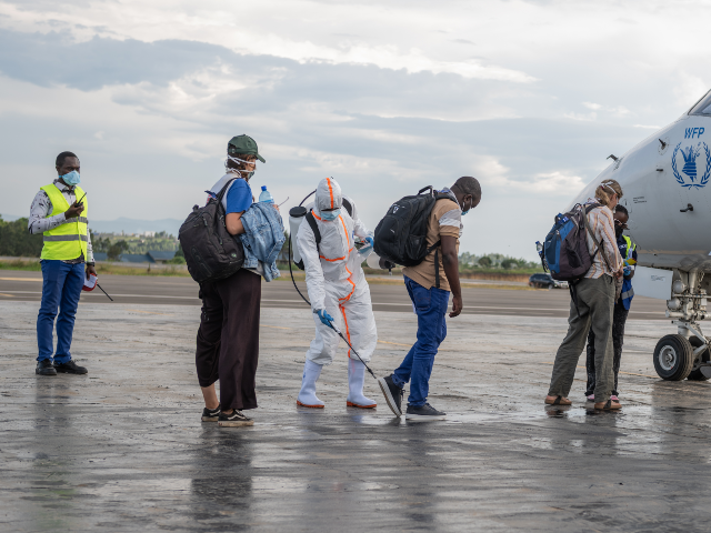 A health worker disinfects passengers prior to their boarding of the World Food Programme&