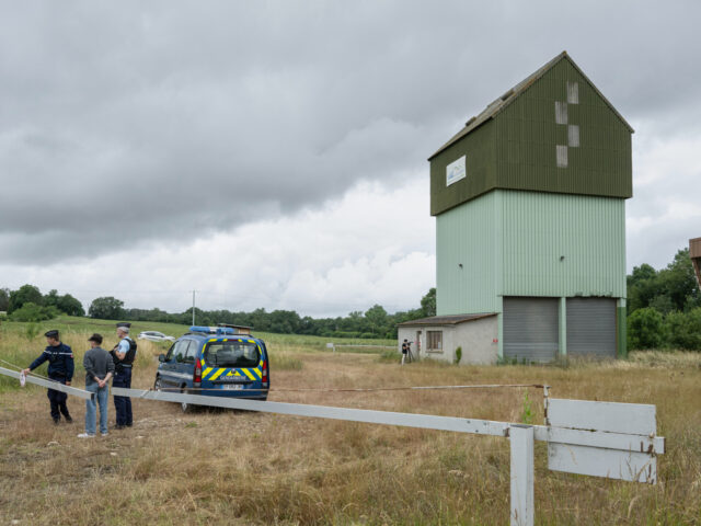 French police guard a farm silo where a body was found yesterday during the search to find
