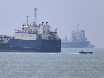 A small motorboat passes anchored vessels in the Strait of Hormuz off Bandar Abbas, Iran,