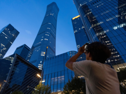A passerby tries to take photo of the damage on the Citic Tower also known as Zun Tower in