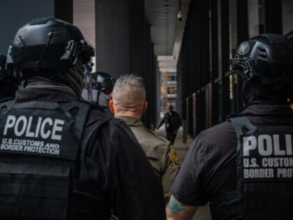 U.S. Border Patrol officers escort Border Patrol commander Gregory Bovino through a crowd