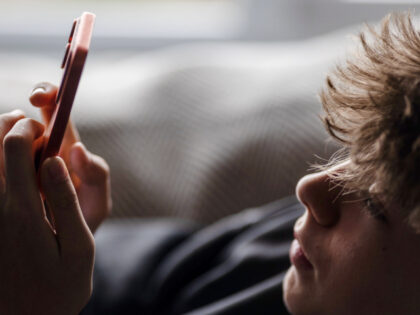 In this photo illustration a 14-year-old boy looks at an iPhone screen displaying various