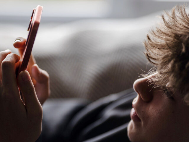 In this photo illustration a 14-year-old boy looks at an iPhone screen displaying various