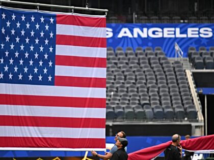 Workers install a US flag above the pitch inside Los Angeles Stadium (temporarily renamed