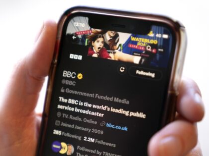 A person holds a smart phone showing the Twitter account for the BBC which has been labell