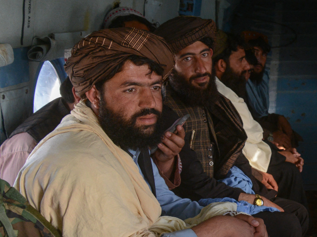 Taliban security personnel travel on a helicopter loaded with food aid packets for distrib