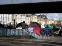 Migrants gather at a temporary migrant camp under an elevated section of Metro line 2, in