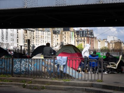 Migrants gather at a temporary migrant camp under an elevated section of Metro line 2, in