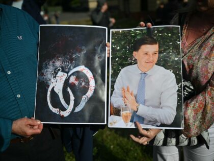 People hold images of victim Henry Nowak, and blood-covered handcuffs as they take part in