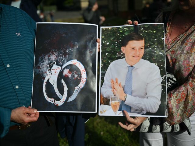 People hold images of victim Henry Nowak, and blood-covered handcuffs as they take part in