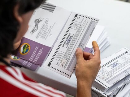 An election worker extracts a mail-in ballot from an envelope following a primary election