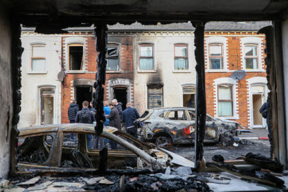 TOPSHOT - People stand next to burnt-out cars and homes after demonstrations turned violen