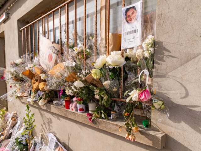 Oblique view of flowers, candles, posters and bouquets arranged on the barred window of th