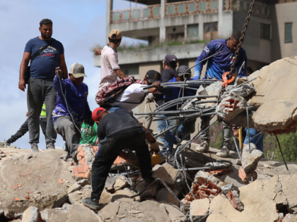 CARACAS, VENEZUELA - JUNE 25: People and rescuers work on the debris of a collapsed buildi