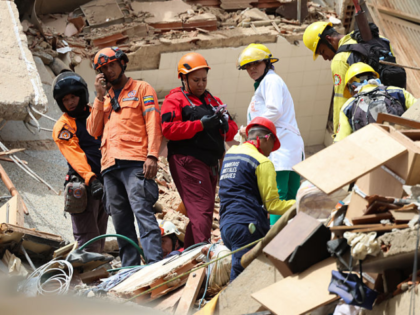 CARACAS, VENEZUELA - JUNE 25: People and rescuers work on the debris of a collapsed buildi
