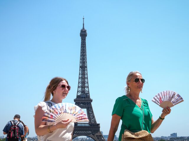 PARIS, FRANCE - JUNE 24: Tourists use folding fans near the Eiffel Tower during hot weathe