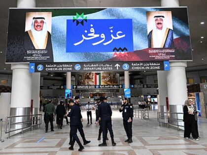 Kuwaiti security officers stand beneath a screen displaying portraits of the Emir of Kuwai