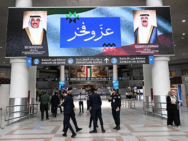 Kuwaiti security officers stand beneath a screen displaying portraits of the Emir of Kuwai