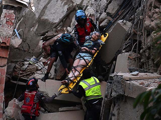 Rescue workers carry a person on a stretcher out of a collapsed building following an eart