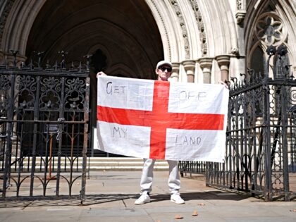 A protester holds an England flag which reads 'Get off my land', outside the High Court, c