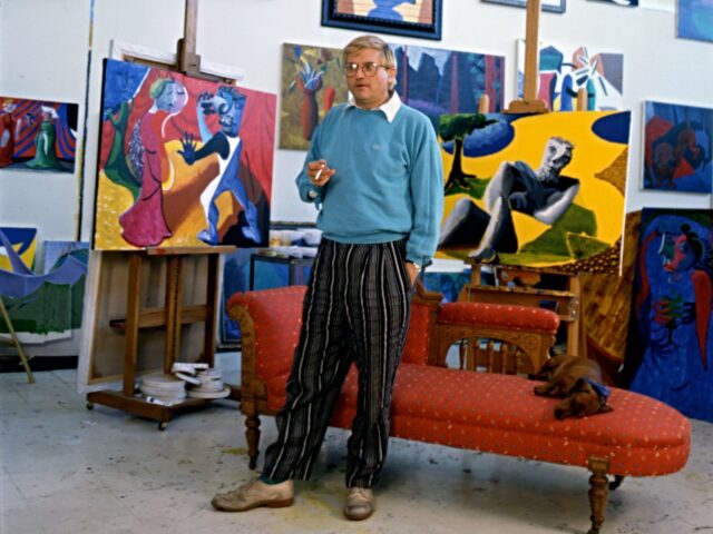 Portrait of English painter David Hockney, dressed in a light blue sweatshirt and tan trou