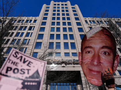 Demonstrators hold a "Save The Post" sign next to a cutout image of Amazon.com Inc. founde