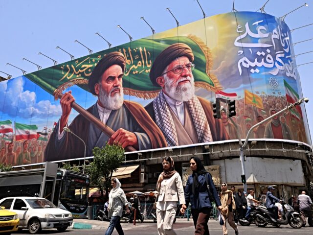 iran no show People cross the street past a large billboard showing portraits of Iran's late supreme le