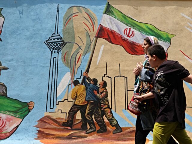 iran responds A woman and boy walk past a nationalistic mural, in Tehran on April 21 2026, amid a ceasef
