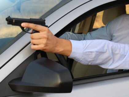 man pointing gun while driving