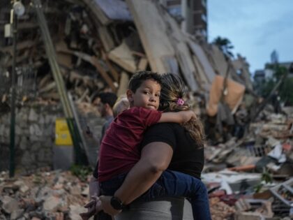 TOPSHOT - People walk past a collapsed building following an earthquake in Caracas on June