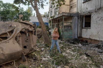 A local resident walks past destroyed cars outside a multi storey residential building dam