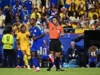 KANSAS CITY, MISSOURI - JUNE 20: Referee Ma Ning shows a yellow card to Gervane Kastaneer