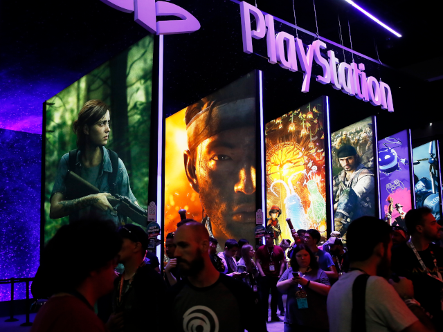 FILE - In this June 14, 2018, file people stand online next to the PlayStation booth at th