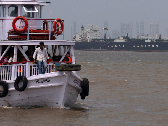 A tourist ferry sails past the Indian flagged LPG carrier Jag Vasant transporting liquefie
