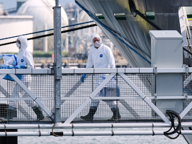 People in protective gear carry items as they disembark the MV Hondius cruise ship after i