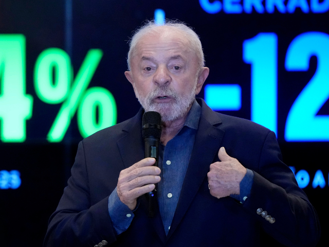 Brazilian President Luiz Inacio Lula da Silva speaks in front of a screen displaying a 61.