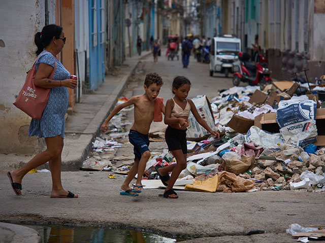 Title: Daily life around the world, in photos Image ID: 26187688185666 Article: Children run past a pile of trash accumulated on a street during a blackout in Havana, Cuba, Monday, July 6, 2026. (AP Photo/Ramon Espinosa)