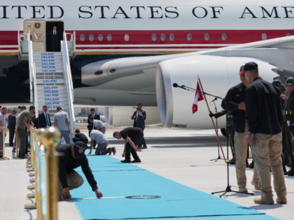 Staff lay a carpet on the tarmac before President Donald Trump exits Air Force One upon ar