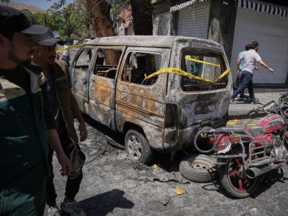 Syrian security personnel inspect a burned vehicles near the Four Seasons Hotel after two
