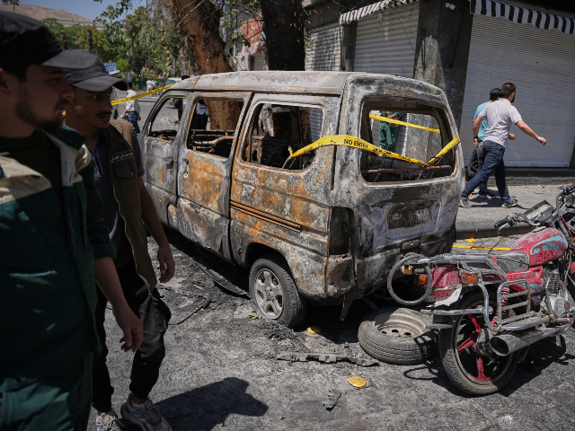 Syrian security personnel inspect a burned vehicles near the Four Seasons Hotel after two