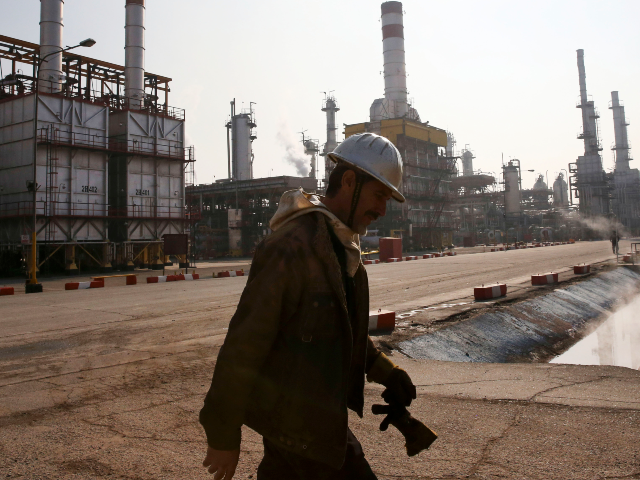 FILE - In this Dec. 22, 2014 file photo, an Iranian oil worker makes his way through Tehra