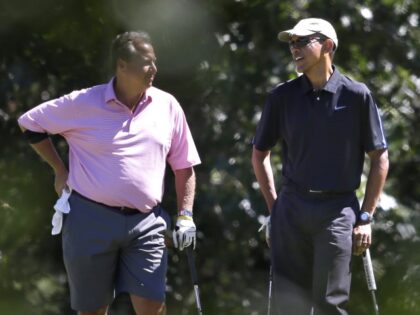 President Barack Obama, right, speaks with golf partner Robert Wolf, left, while golfing a