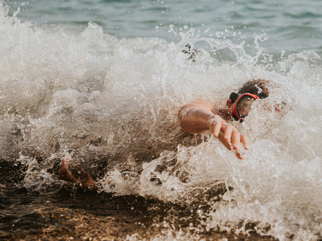 Boy in ocean waves reaching out