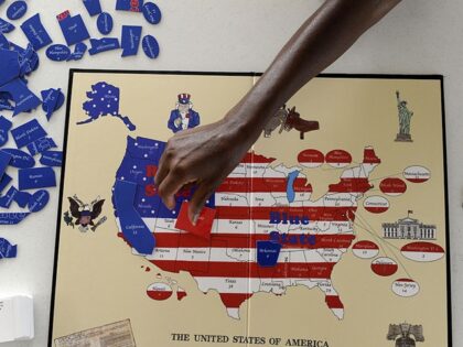Sherri Pollard, places a game piece on the Red State Blue State political board game creat