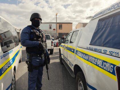 A South African policeman secure the perimeter while a house is searched for guns, drugs a